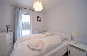 a white bedroom with a white bed and a window at Apart-Invest Apartament Oslo in Szklarska Poręba