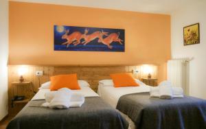 2 camas en una habitación de hotel con paredes de color naranja en Indren Hus, en Alagna Valsesia