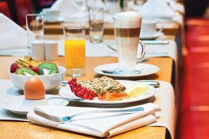 a table topped with plates of food and drinks at Mövenpick Hotel Berlin Am Potsdamer Platz in Berlin