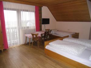 una habitación con dos camas y una mesa y sillas en Pension Elsendorf, en Elsendorf