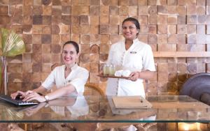 dos mujeres de pie junto a una mesa con un portátil en Seasense Boutique Hotel & Spa, en Belle Mare