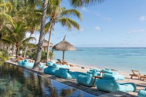 una piscina sulla spiaggia con palme e l'oceano di Seasense Boutique Hotel & Spa a Belle Mare