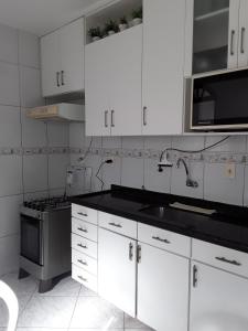 kuchnia z białymi szafkami, zlewem i kuchenką w obiekcie Casa na praia de Aruana w mieście Atalaia Velha