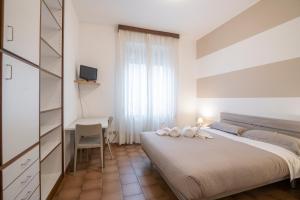 a white bedroom with a bed and a desk at Residenza Miola in Saronno