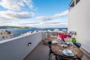 d'un balcon avec des tables et des chaises et une vue sur l'eau. dans l'établissement Seashells 2 bedroom Apartment with sunny terrace with stunning sea views - by Getawaysmalta, à San Pawl il-Baħar