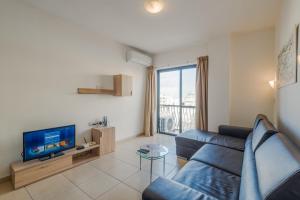 un soggiorno con divano blu e TV di Seashells Apartments with terrace, just off the seafront in Bugibba - by Getawaysmalta a San Pawl il-Baħar