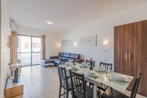 a dining room and living room with a table and chairs at Seashells Apartments with terrace, just off the seafront in Bugibba - by Getawaysmalta in St Paul's Bay