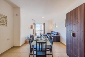 a dining room with a table and chairs and a couch at Seashells Apartments with terrace, just off the seafront in Bugibba - by Getawaysmalta in St. Paul's Bay