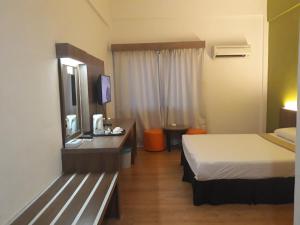 a hotel room with a bed and a desk with a television at Hotel Seri Malaysia Temerloh in Temerloh