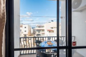 a balcony with a table and a view of a city at Seashells Apartments with terrace, just off the seafront in Bugibba - by Getawaysmalta in St. Paul's Bay