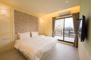 a bedroom with a white bed and a window at Yilan Siao Jhu in Jiaoxi