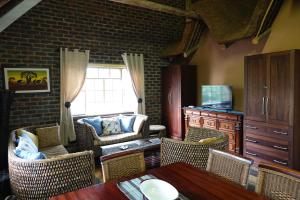 een woonkamer met stoelen en een tafel en een raam bij Marloth Park Hippo House in Marloth Park