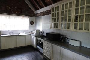 een keuken met witte kasten, een spoelbak en een magnetron bij Marloth Park Hippo House in Marloth Park