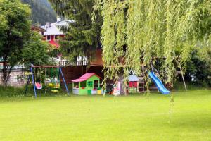 a park with a playground with a tree and swings at Hotel Stecher in Oetz