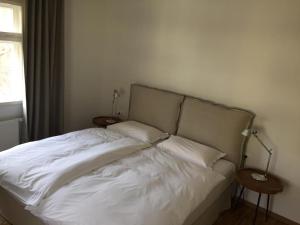 uma cama com lençóis brancos e almofadas num quarto em Achtzimmer em Würzburg