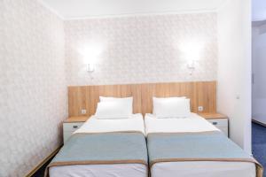 a bedroom with two beds and two lights on the wall at Hotel Snegiri in Syktyvkar