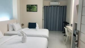 a hotel room with two beds and a couch at Wisdom Hotel in Samut Songkhram