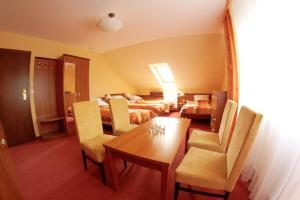 Habitación de hotel con mesa de comedor y dormitorio en Pensjonat Żagielek, en Augustów