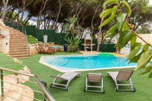 a swimming pool with two chairs and a table at Eco Geo Sol in Lloret de Mar