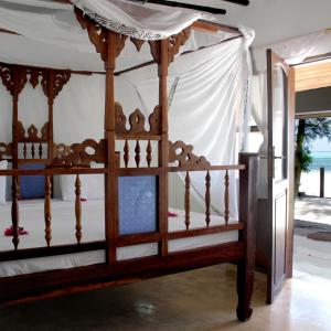 a wooden bed with a canopy in a room at Panga Chumvi Beach Resort in Matemwe