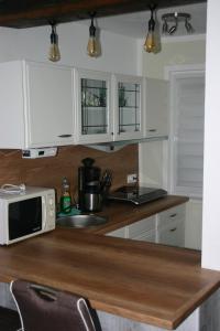 een keuken met witte kasten en een magnetron op een aanrecht bij Ferienwohnung Am See 55 in Bad Saarow