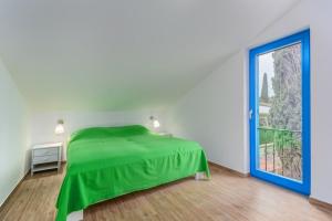 ein Schlafzimmer mit einem grünen Bett und einem großen Fenster in der Unterkunft Dajla 66 in Dajla