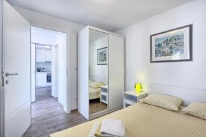 a white bedroom with a mirror and a bed at Apartmani ATL in Rogoznica
