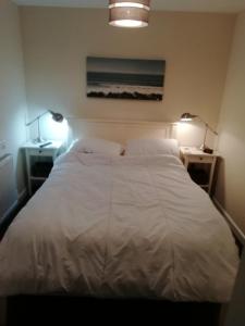 een slaapkamer met een groot wit bed met 2 lampen bij The Studio in Georgeham