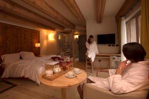Una mujer en una habitación con una cama y un hombre hablando por teléfono. en Chalet Prà delle Nasse, en San Martino di Castrozza