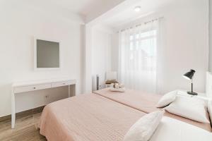 フンシャルにあるFunchal City Apartmentsの白いベッドルーム(ベッド1台、テレビ付)