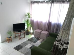 ein Wohnzimmer mit einem grünen Sofa und einem TV in der Unterkunft Natal RN Apartamento in Parnamirim