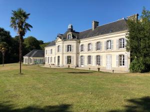 uma grande casa branca com uma palmeira em frente em Château de Lannouan em Landévant