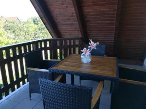 einen Holztisch mit Stühlen und eine Vase mit Blumen auf der Veranda in der Unterkunft Ferienwohnung im Harz in Wienrode