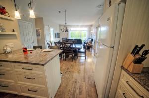 a kitchen with a white refrigerator and a dining room at Chalet Potvin Bouchard in LʼAnse-Saint-Jean