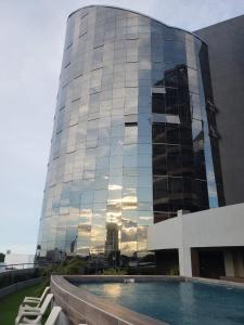 ein hohes Glasgebäude mit einem Pool davor in der Unterkunft Torres Evolution in Santa Cruz de la Sierra