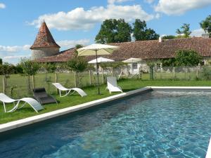 a pool with chairs and an umbrella next to a house at Chambres d'Hôtes et Gîtes du Château de Clauzuroux in Champagne-et-Fontaine