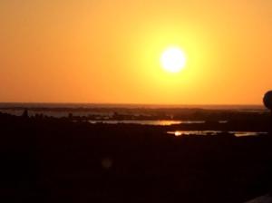 una puesta de sol sobre un cuerpo de agua con el sol en Ocean Sunshine, en Orzola