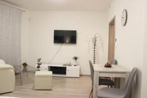 a living room with a table and a tv on a wall at H+ Apartman Letiště Praha in Prague