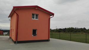 un pequeño edificio naranja con una ventana y un campo en Apartmány Klimkovice, en Klimkovice