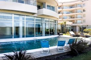 a swimming pool with chairs next to a building at Azure Punta Executive in Punta del Este