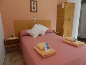 Un dormitorio con una cama rosa con toallas. en Hotel El Parque en San Clemente del Tuyú