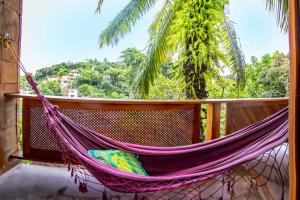 a hammock on a balcony with a palm tree at Pousada Tímia in Morro de São Paulo