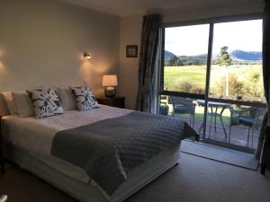 a bedroom with a bed and a balcony with a view at Kinloch Lake & Golf Views in Kinloch