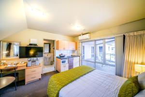 a bedroom with a bed and a desk and a television at CentrePoint on Colombo in Christchurch