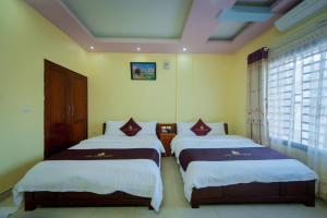 
two beds in a room with two windows at Lam Tung Hotel in Dồng Văn
