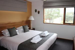 Lake Crackenback Resort & Spa في كراكينباك: غرفة نوم عليها سرير وفوط