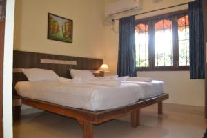 a large white bed in a room with windows at The Majorda Pristinne in Majorda