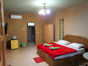 Un dormitorio con una cama con sábanas rojas y una mesa. en Baandin resort, en Sukhothai