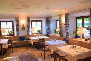 restauracja ze stołami, krzesłami i oknami w obiekcie Seehotel Huber w mieście St. Gilgen