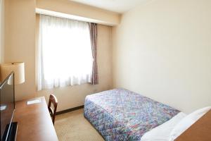 a hotel room with a bed and a window at Marroad Inn Hachioji in Hachioji